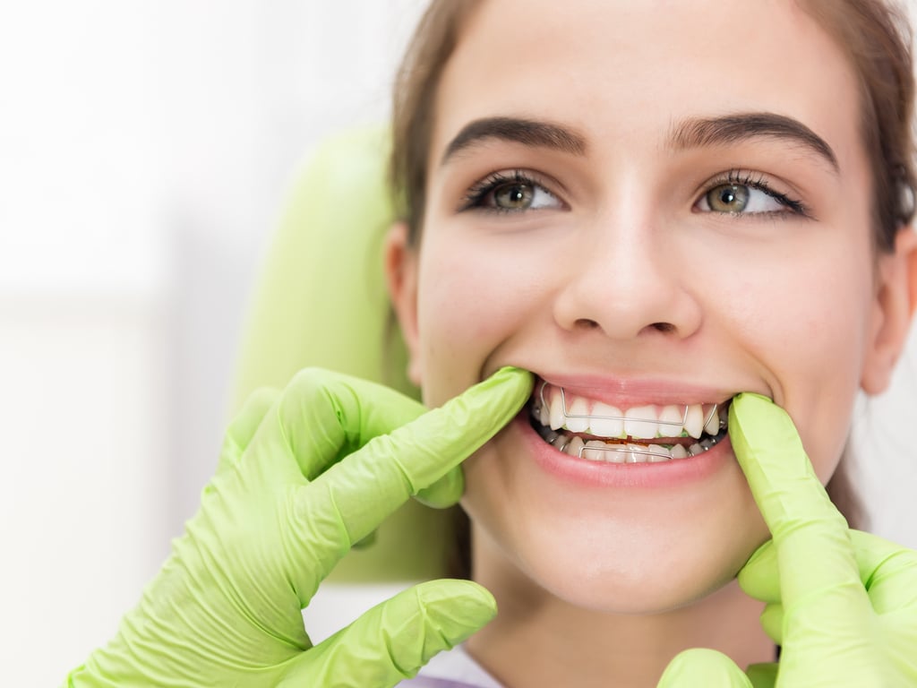 femme avec appareil dentaire et mains de dentiste avec gants verts